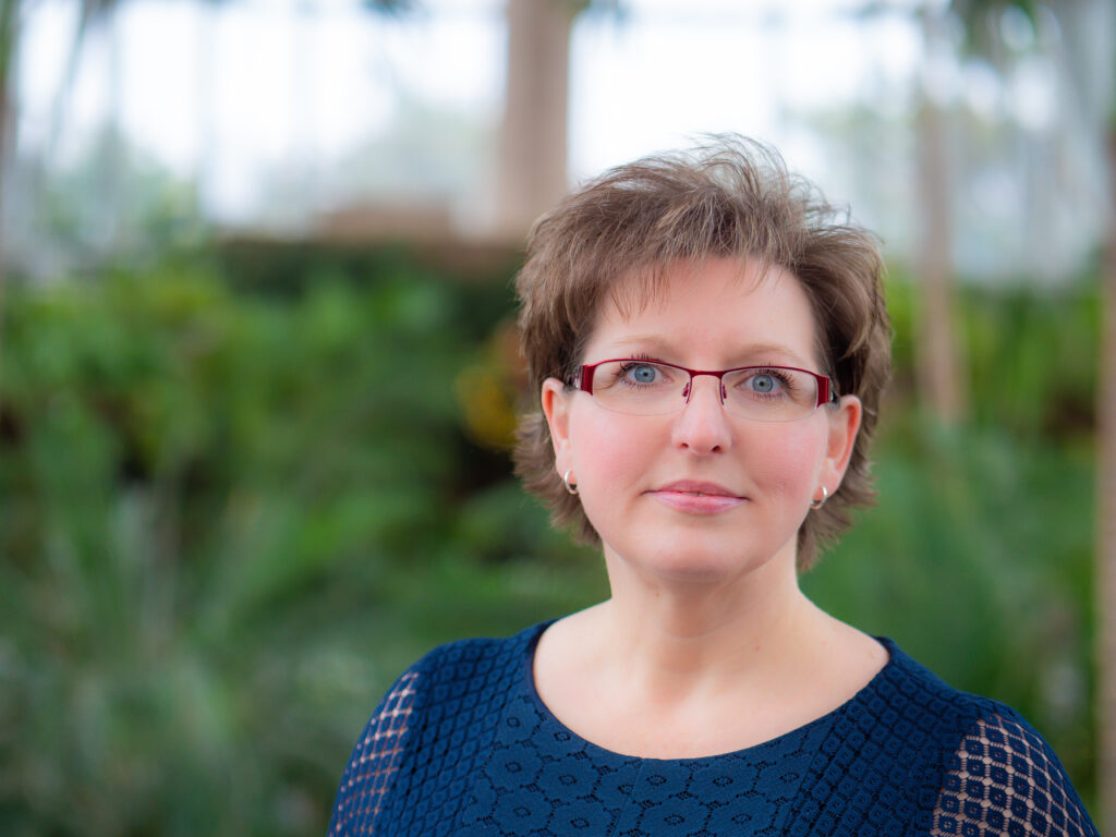 Portrait of a woman wearing glasses and a blue top.